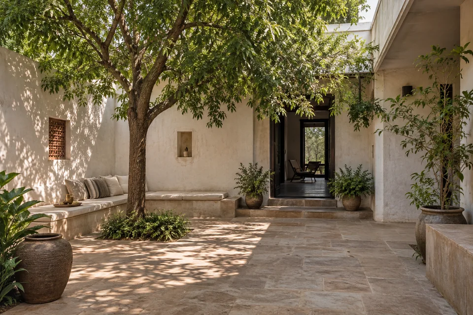 AI-generated concept: Private house courtyard with sandstone paving, low seating ledge, neem-like leafy tree, textured off-white walls, shaded doorway.
