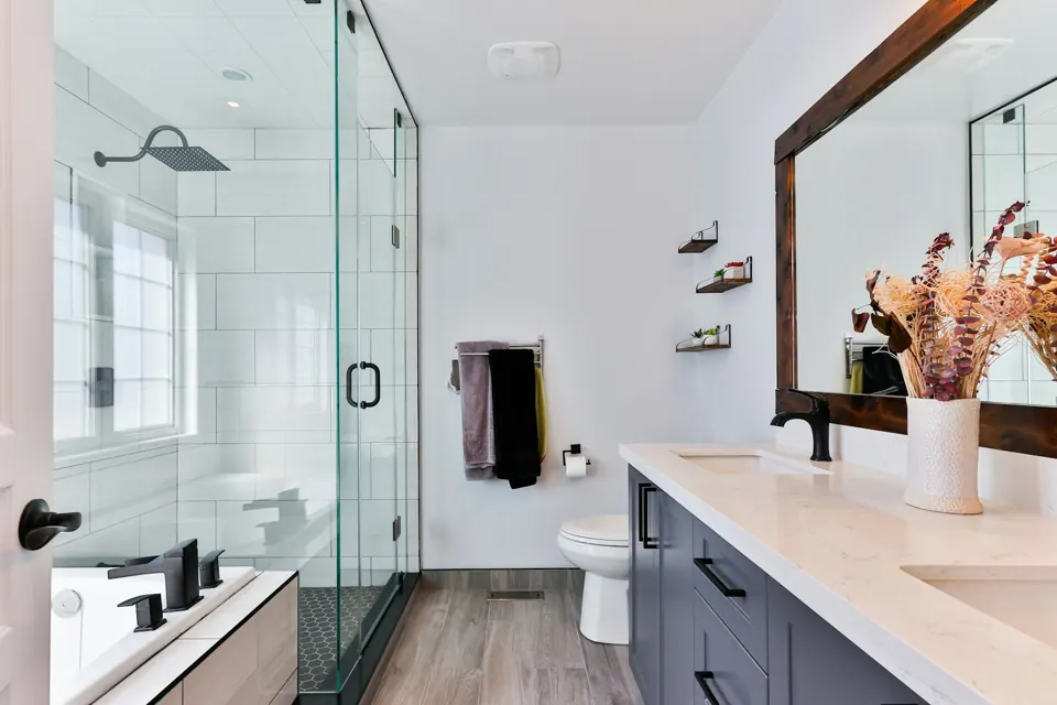 Bathroom with a glass shower, timber-framed mirror and dark vanity