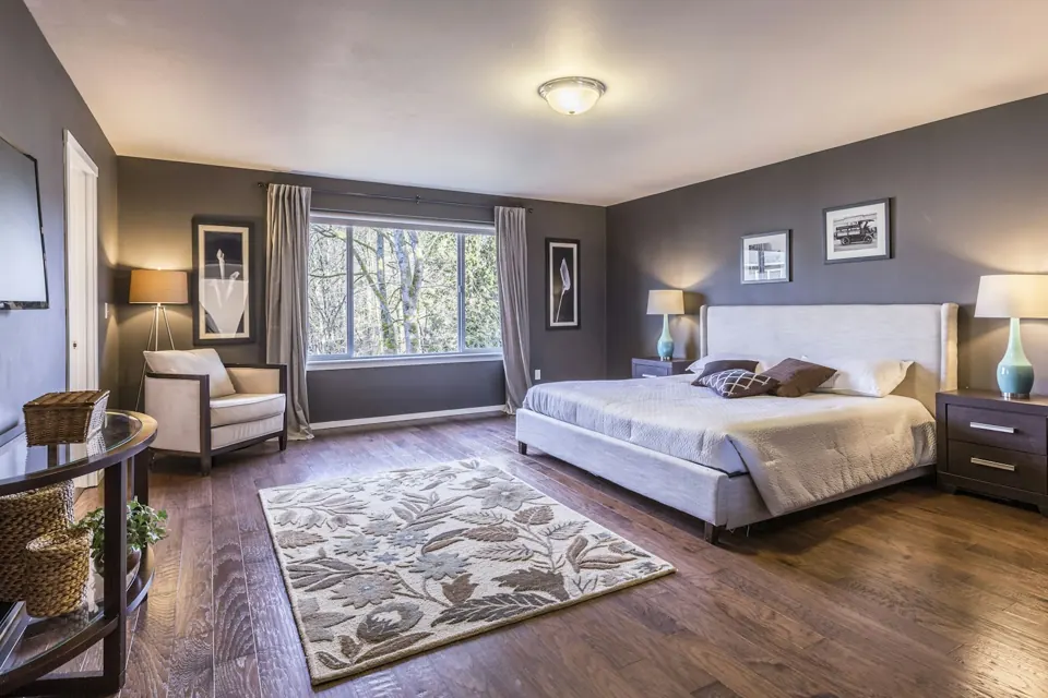 Bedroom with a large patterned rug, soft upholstered bed and wide window