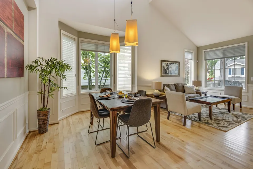 Bright dining area with upholstered chairs, pendant lights and garden-facing windows