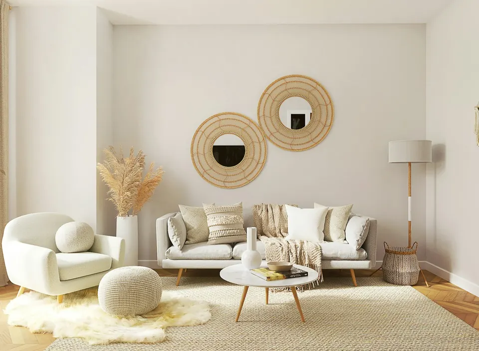 Cream seating, round woven mirrors and a sculptural coffee table in a bright living room